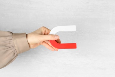 Photo of Woman with horseshoe magnet on light background, closeup