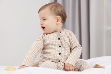 Photo of Adorable little baby with toy on bed at home