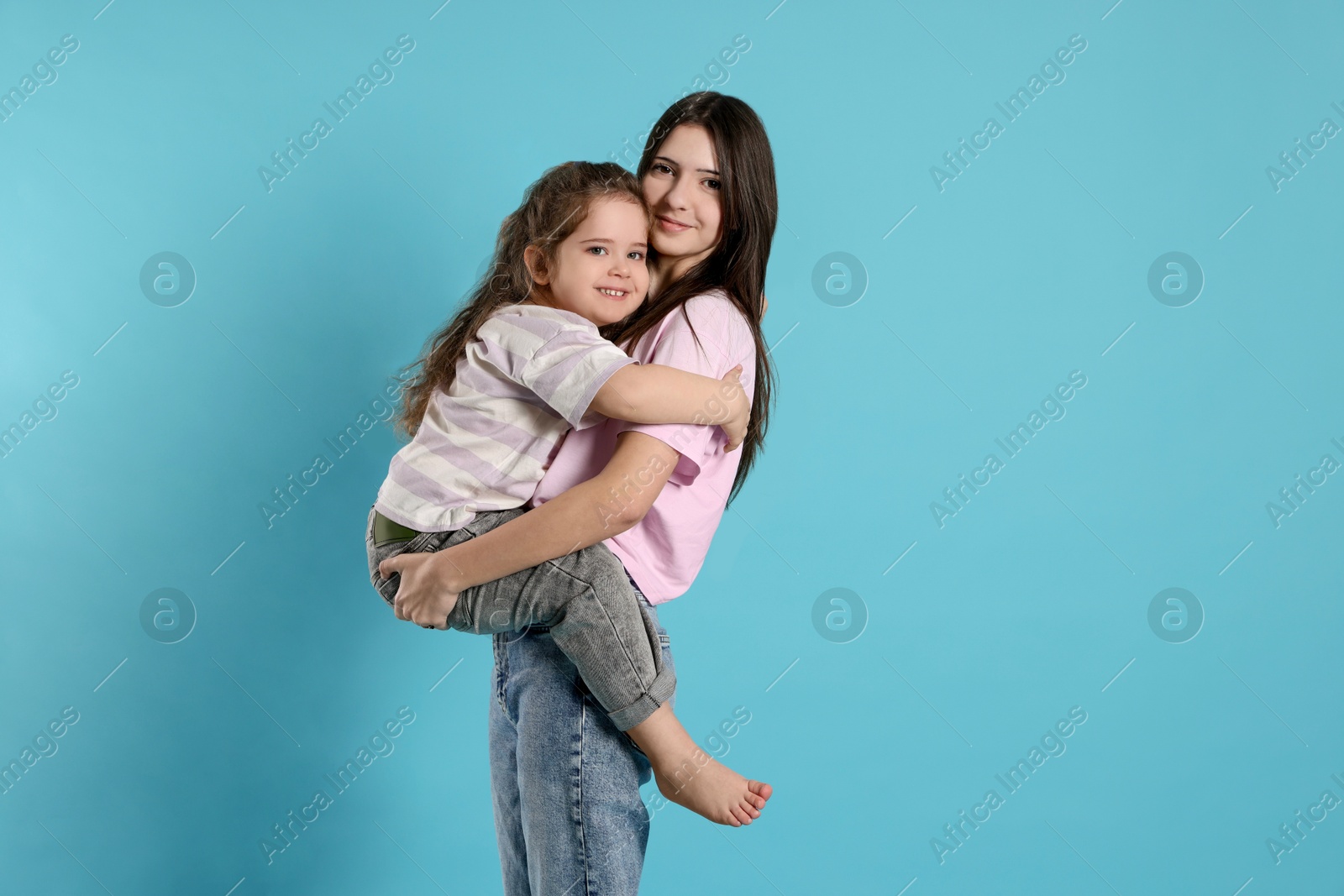 Photo of Portrait of cute sisters on light blue background