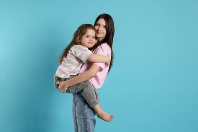 Photo of Portrait of cute sisters on light blue background