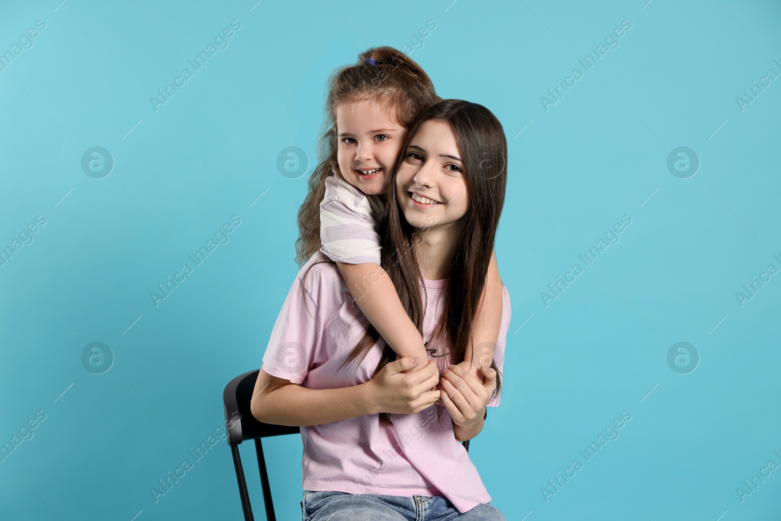 Photo of Portrait of cute sisters on light blue background