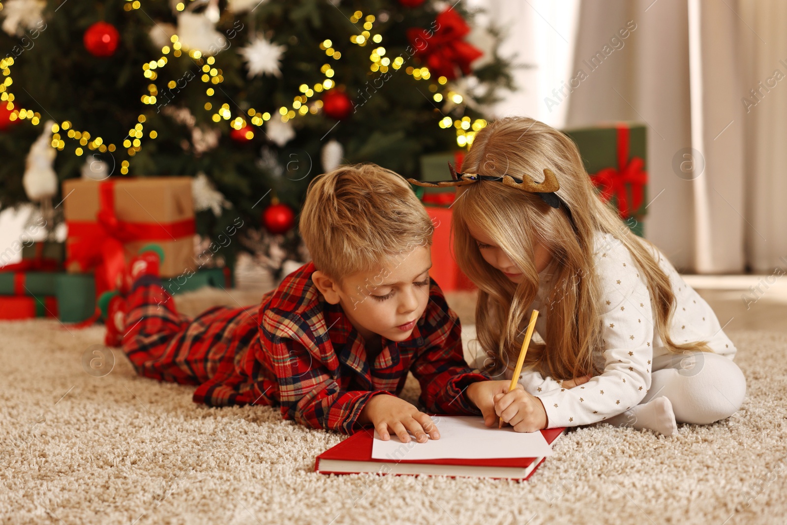 Photo of Little kids writing letter to Santa Claus on floor at home. Christmas celebration