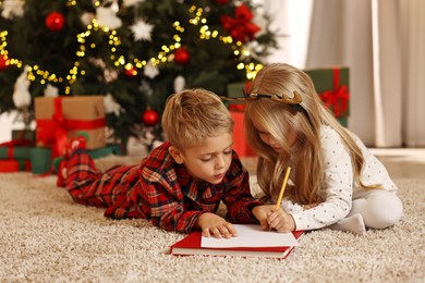 Little kids writing letter to Santa Claus on floor at home. Christmas celebration