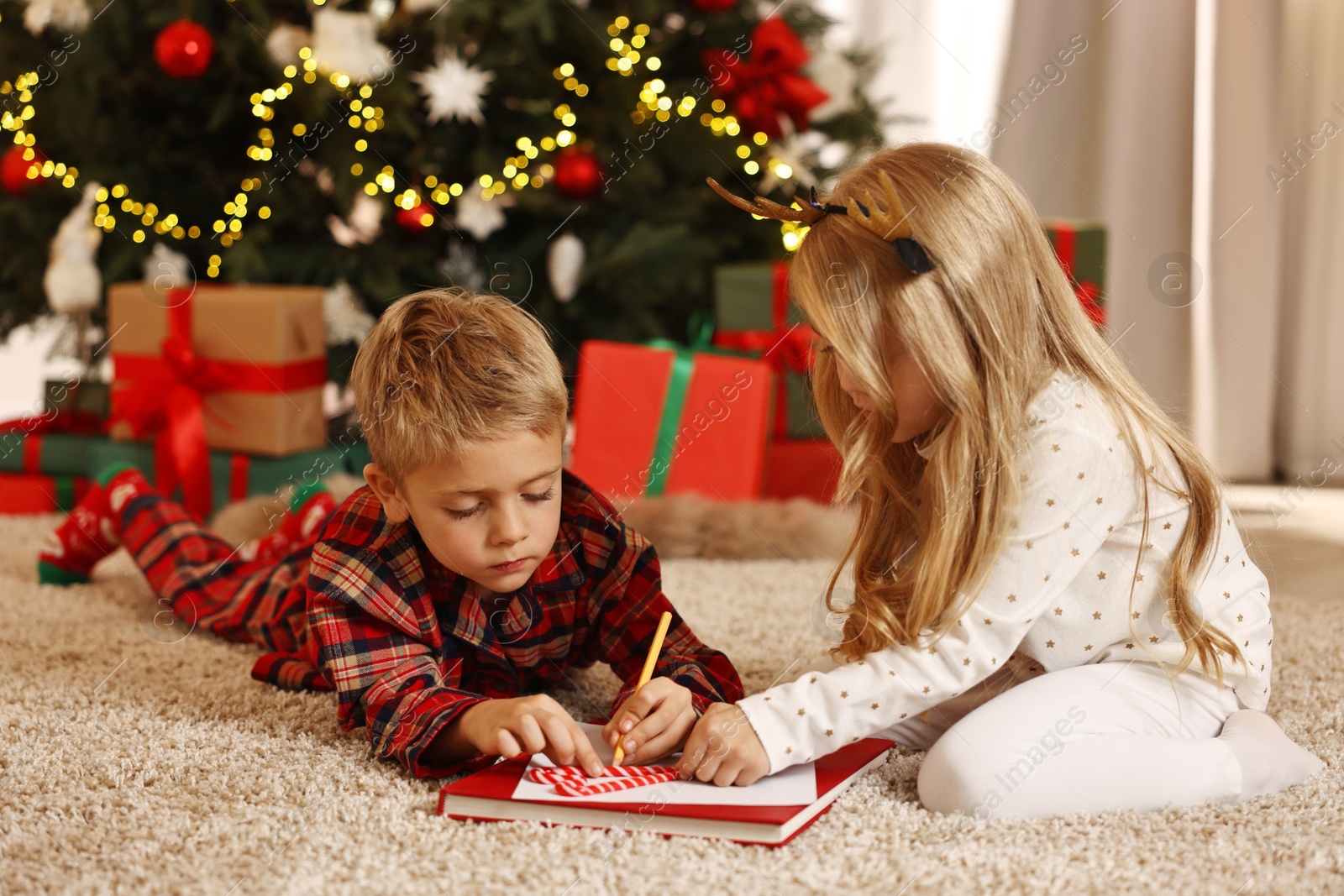 Photo of Little kids writing letter to Santa Claus on floor at home. Christmas celebration