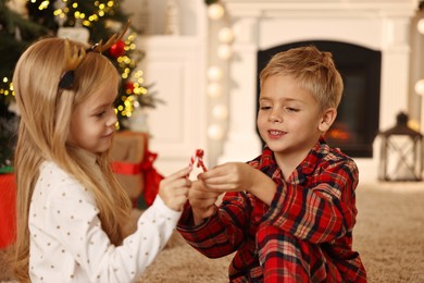 Photo of Little kids with candy canes on floor at home. Christmas celebration