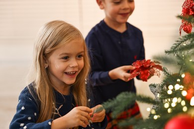 Little kids decorating Christmas tree at home