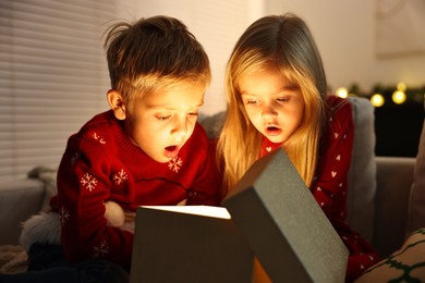 Surprised little kids near open magic Christmas box at home