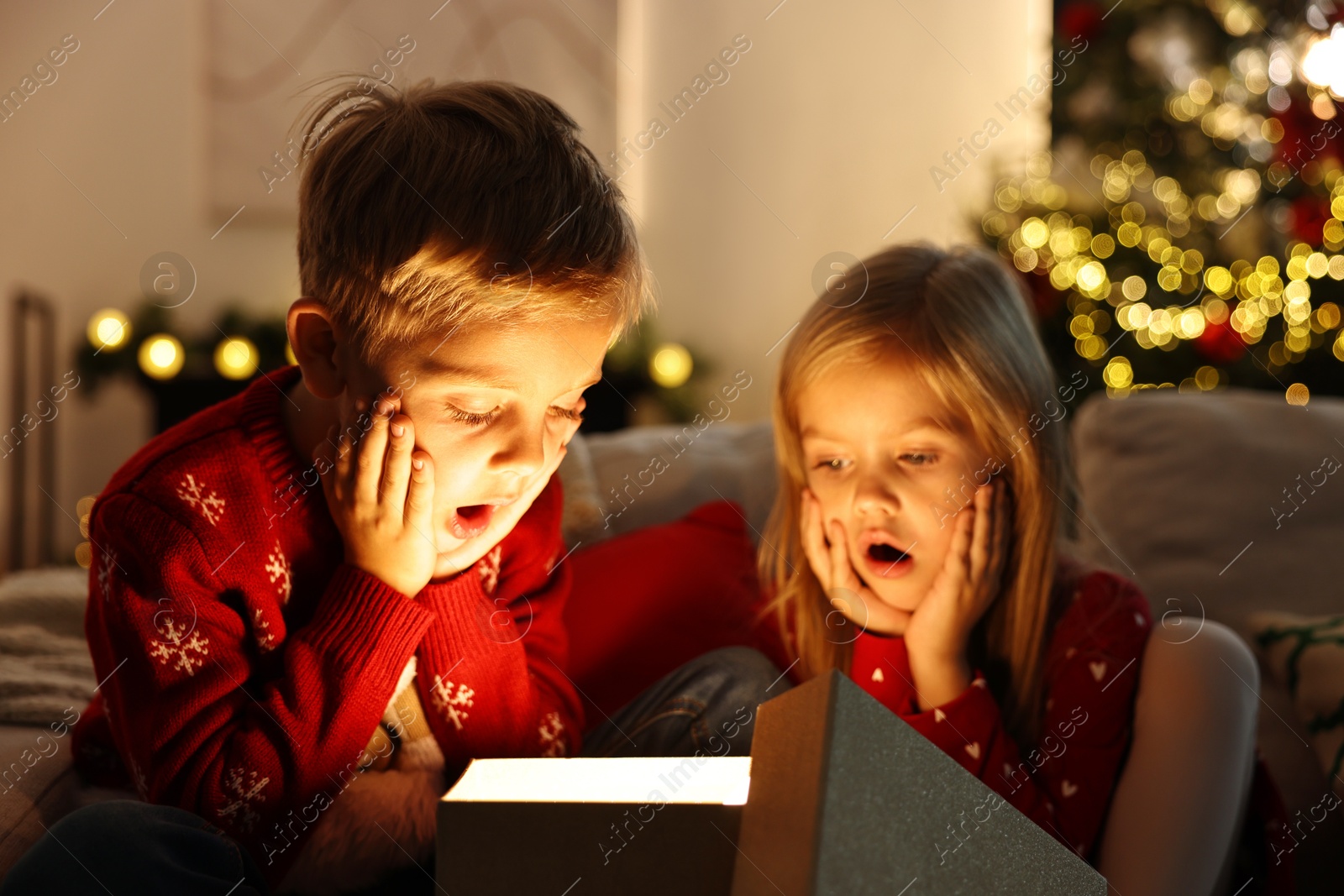 Photo of Surprised little kids near open magic Christmas box at home