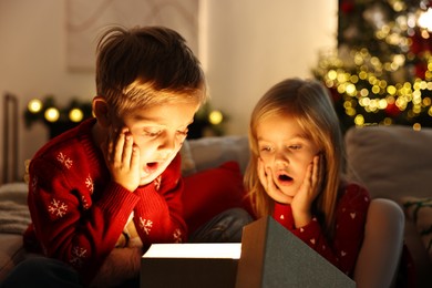 Surprised little kids near open magic Christmas box at home