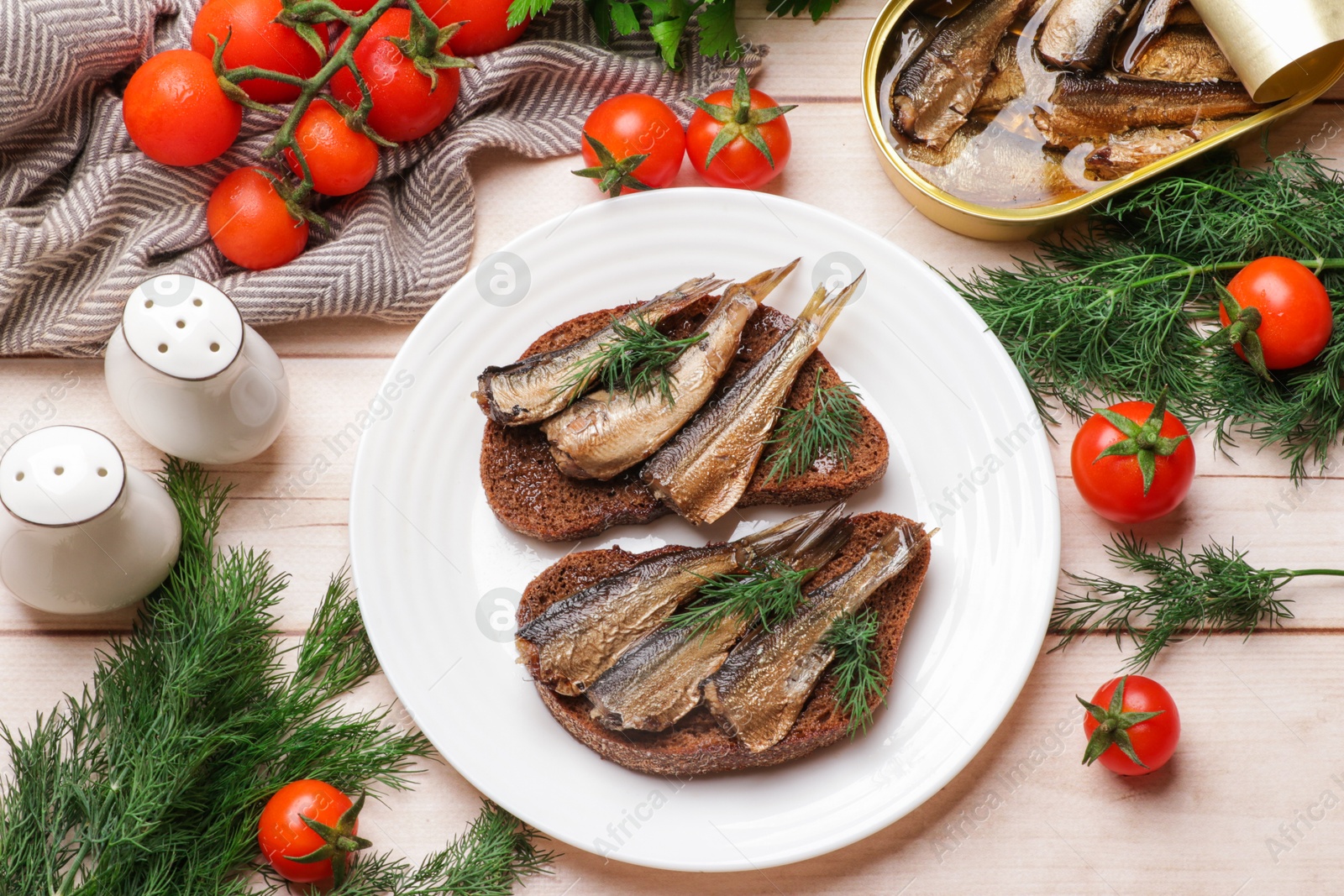 Photo of Delicious sandwiches with sprats and dill served on white wooden table, top view