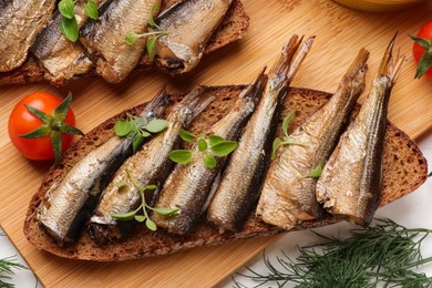 Photo of Delicious sandwiches with sprats, microgreens and dill on white table, top view