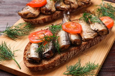 Photo of Delicious sandwiches with sprats, dill and tomato on table, closeup