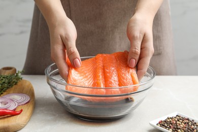 Photo of Woman with salmon fillet and soy sauce at gray table, closeup