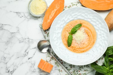 Photo of Delicious sweet potato soup served on white marble table, flat lay