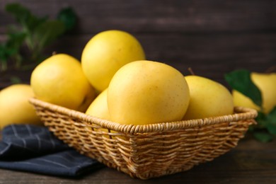 Photo of Fresh yellow apples in wicker basket on table, closeup