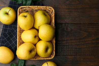 Photo of Fresh yellow apples in wicker basket on wooden table, top view. Space for text