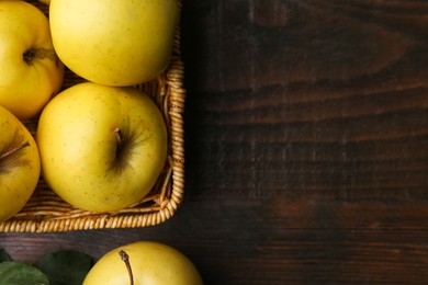 Photo of Fresh yellow apples in wicker basket on wooden table, top view. Space for text