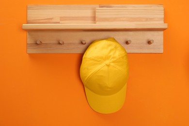 Photo of Stylish baseball cap on orange wall. Mockup for design