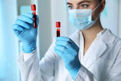 Laboratory testing. Doctor holding test tubes with blood samples indoors, selective focus