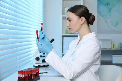 Photo of Laboratory testing. Doctor holding test tubes with blood samples at table indoors