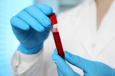 Photo of Laboratory testing. Doctor holding test tube with blood sample indoors, closeup