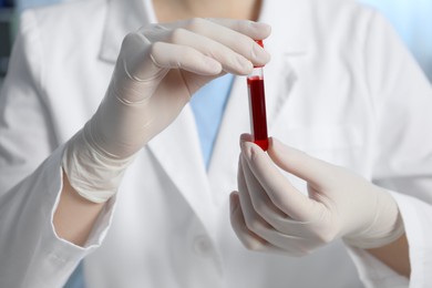 Photo of Laboratory testing. Doctor holding test tube with blood sample indoors, closeup