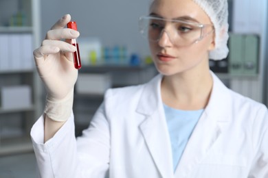 Photo of Laboratory testing. Doctor holding test tube with blood sample indoors, selective focus