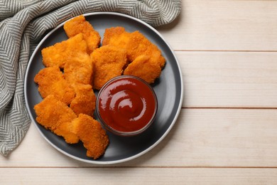 Photo of Tasty chicken nuggets and sauce on wooden table, top view. Space for text