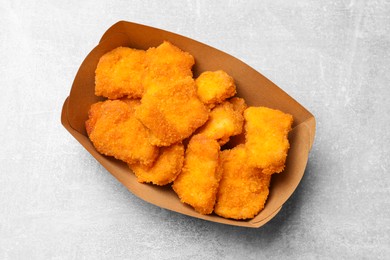 Photo of Delicious chicken nuggets in carton box on light table, top view