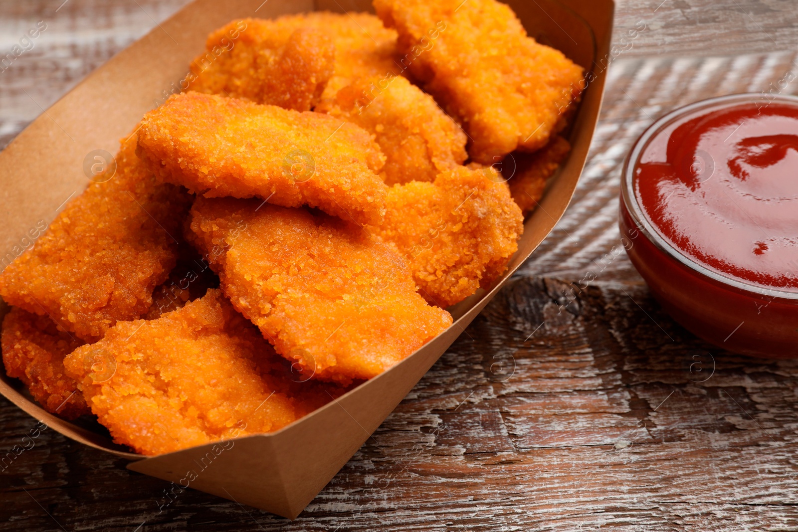 Photo of Delicious chicken nuggets with ketchup on wooden table, closeup