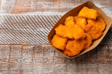 Photo of Delicious chicken nuggets on wooden table, top view. Space for text