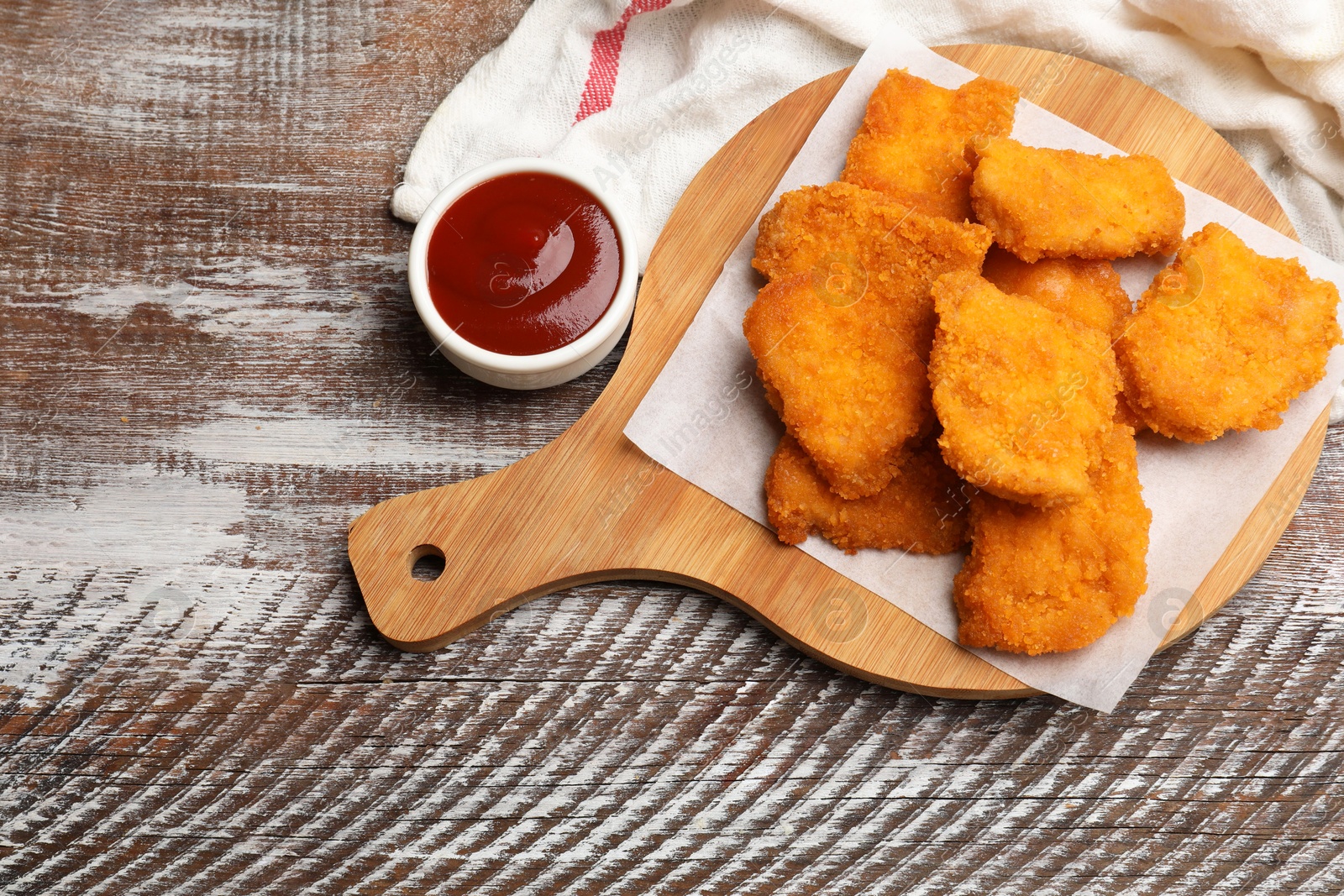 Photo of Delicious chicken nuggets with ketchup on wooden table, above view