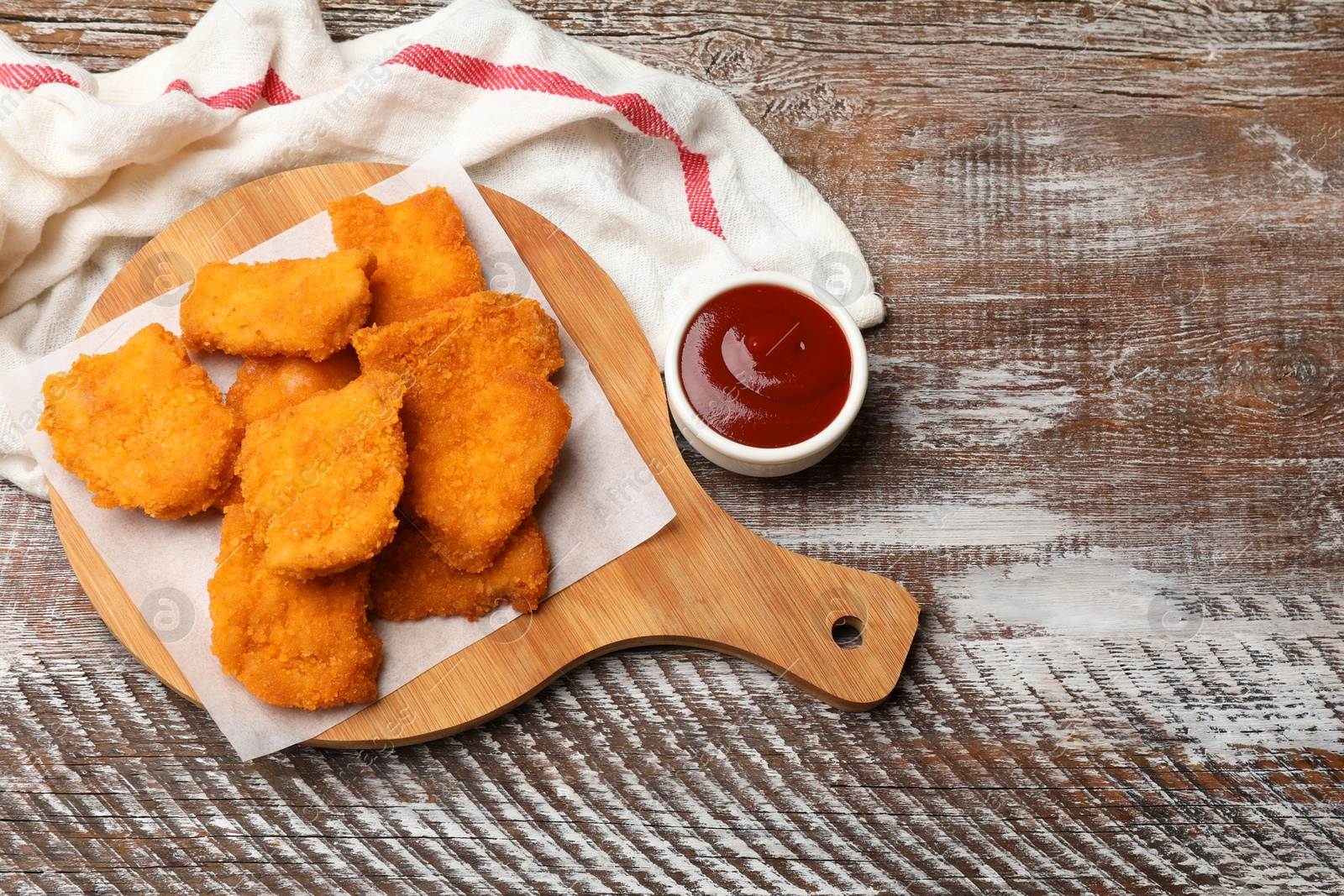 Photo of Delicious chicken nuggets with ketchup on wooden table, above view. Space for text