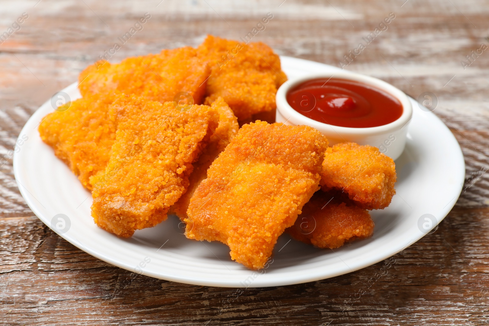 Photo of Delicious chicken nuggets with ketchup on wooden table, closeup