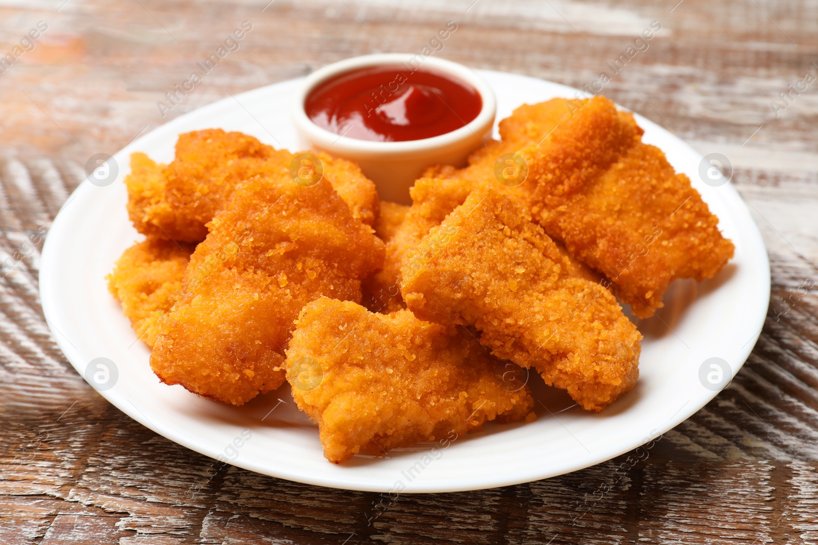 Photo of Delicious chicken nuggets with ketchup on wooden table, closeup