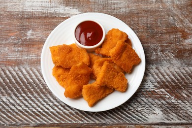 Photo of Delicious chicken nuggets with ketchup on wooden table, top view