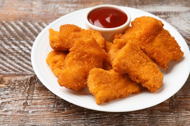 Photo of Delicious chicken nuggets with ketchup on wooden table, closeup