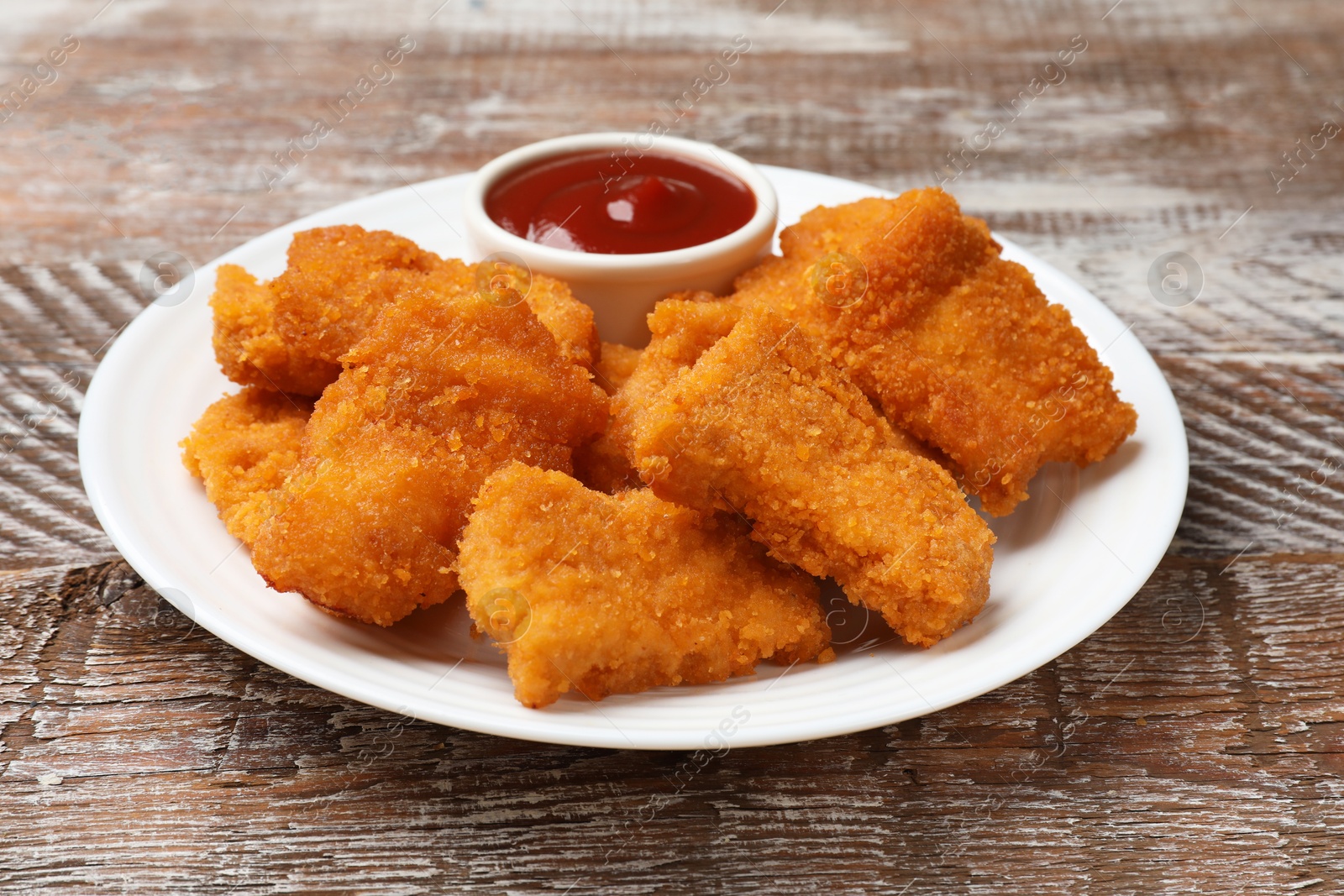 Photo of Delicious chicken nuggets with ketchup on wooden table, closeup