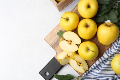 Photo of Ripe yellow apples and leaves on light grey table, top view. Space for text