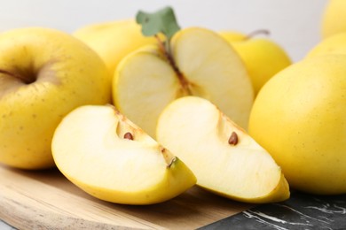 Photo of Whole and cut ripe yellow apples on table, closeup