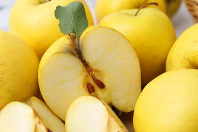 Whole and cut ripe yellow apples on table, closeup