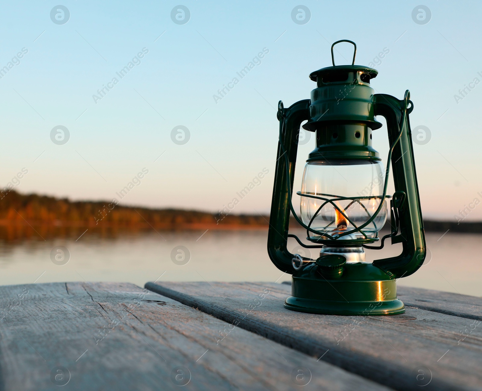 Photo of Vintage kerosene lamp on wooden surface in evening. Space for text