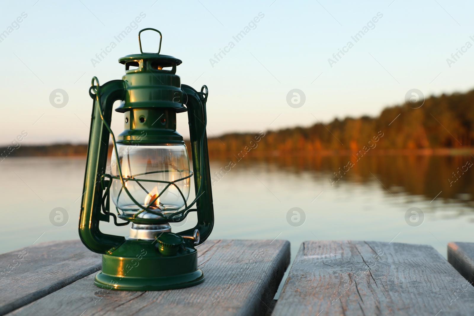 Photo of Vintage kerosene lamp on wooden surface in evening. Space for text