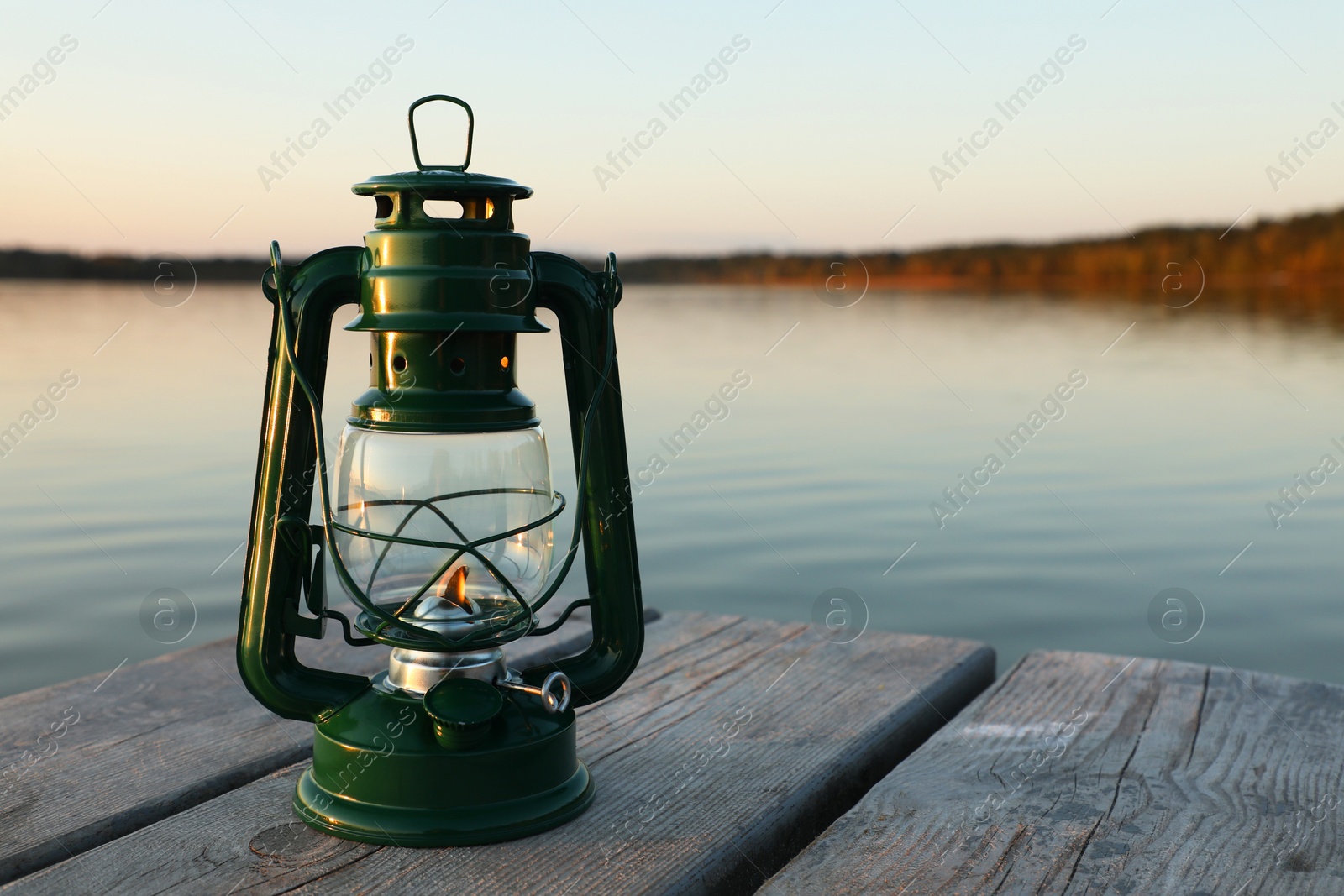 Photo of Vintage kerosene lamp on wooden surface in evening. Space for text