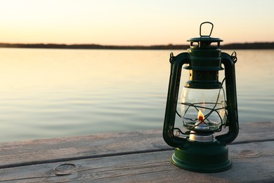 Photo of Vintage kerosene lamp on wooden surface in evening. Space for text