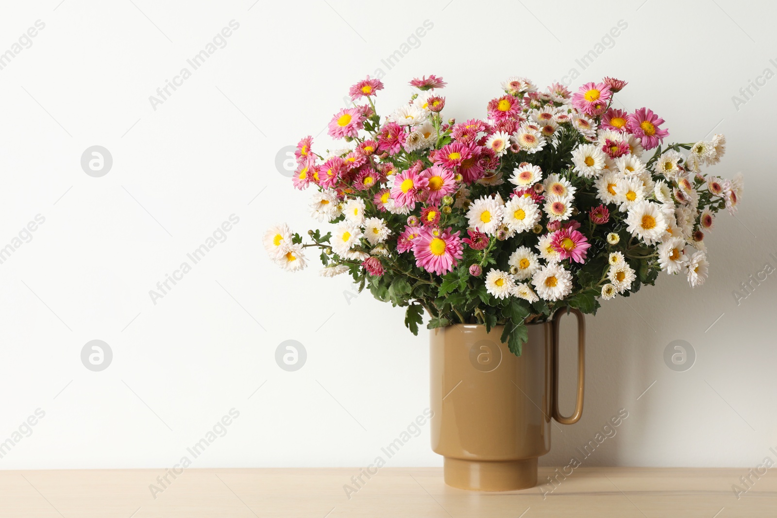 Photo of Vase with beautiful flowers on wooden table, space for text