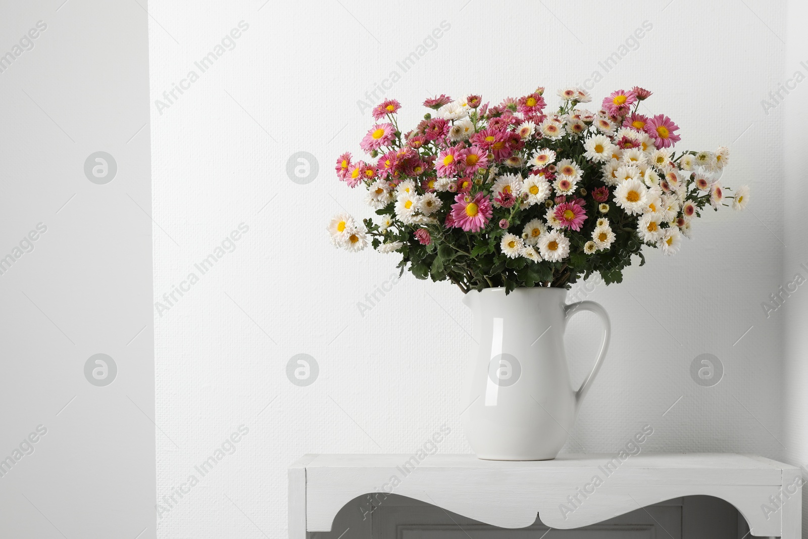 Photo of Vase with beautiful flowers on white shelving unit