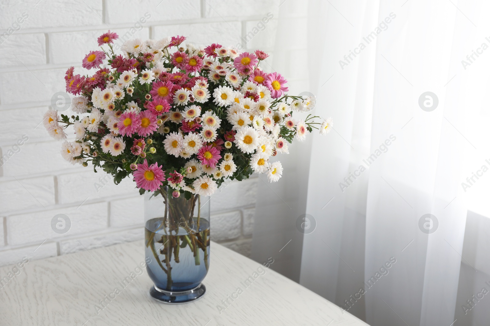 Photo of Vase with beautiful flowers on white wooden table. Space for text