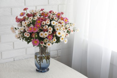 Photo of Vase with beautiful flowers on white wooden table. Space for text