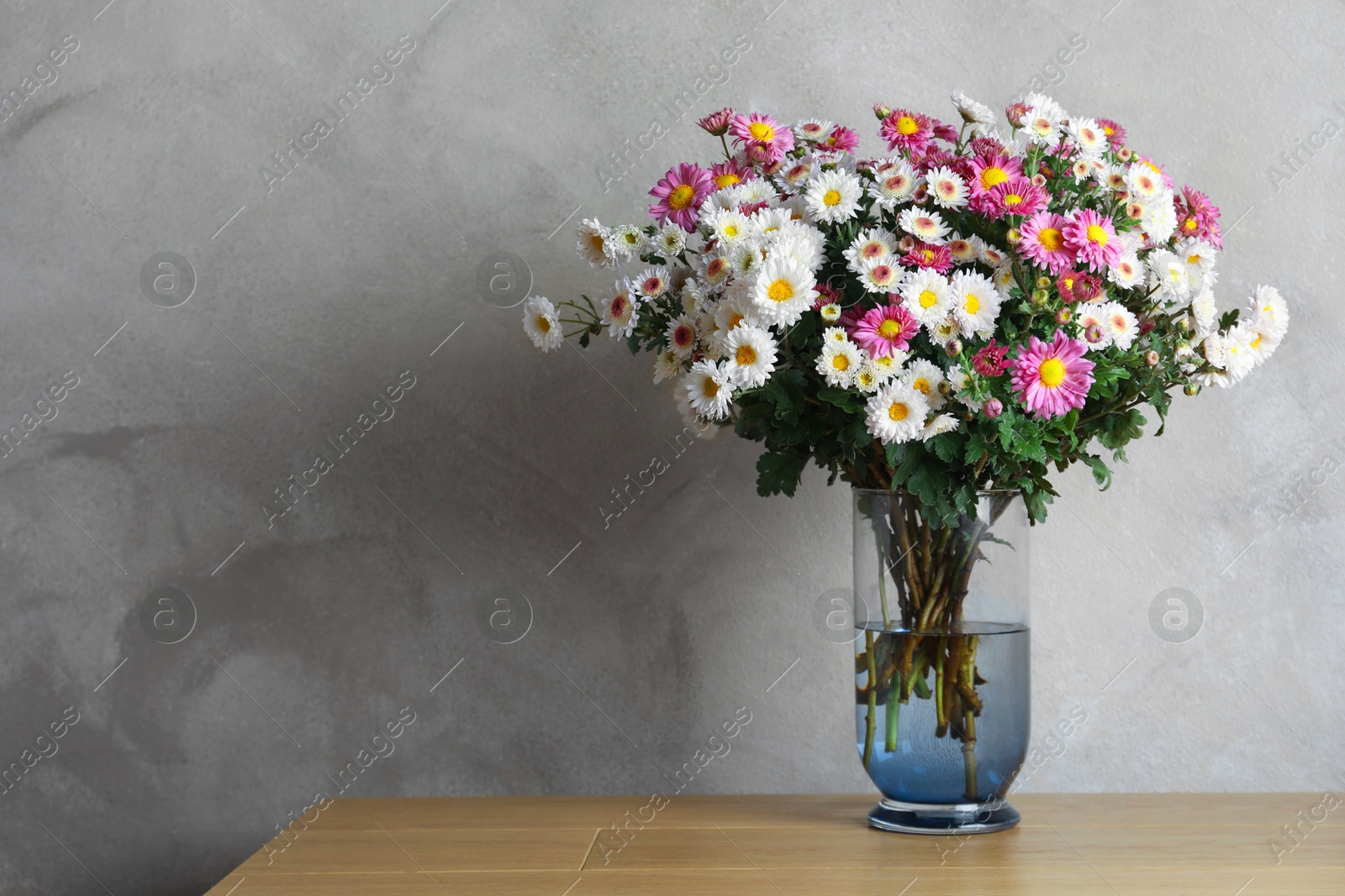 Photo of Vase with beautiful flowers on pink wooden table. Space for text